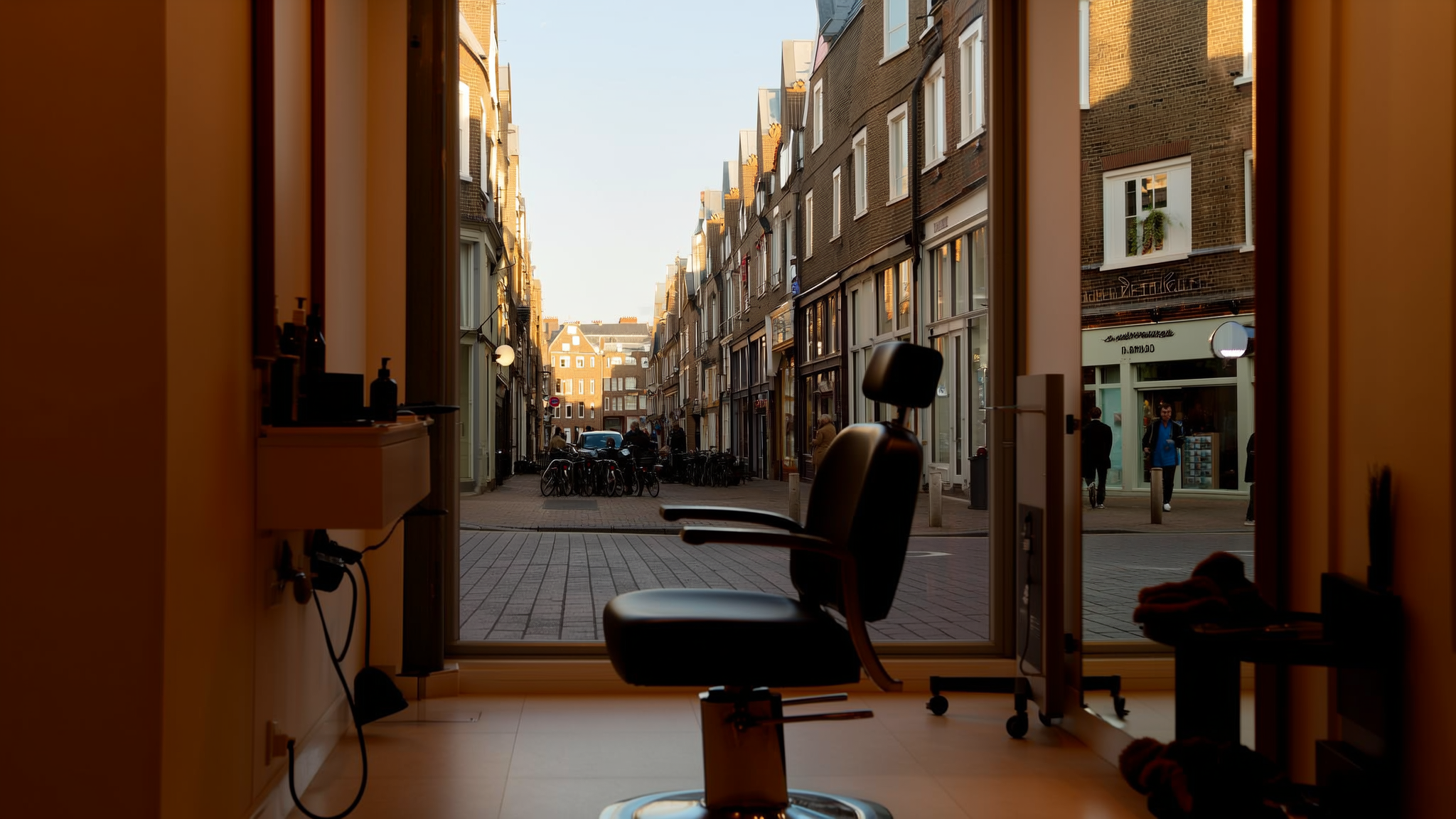 Kappersstoel voor een groot raam met uitzicht op een winkelstraat in de ochtendzon
