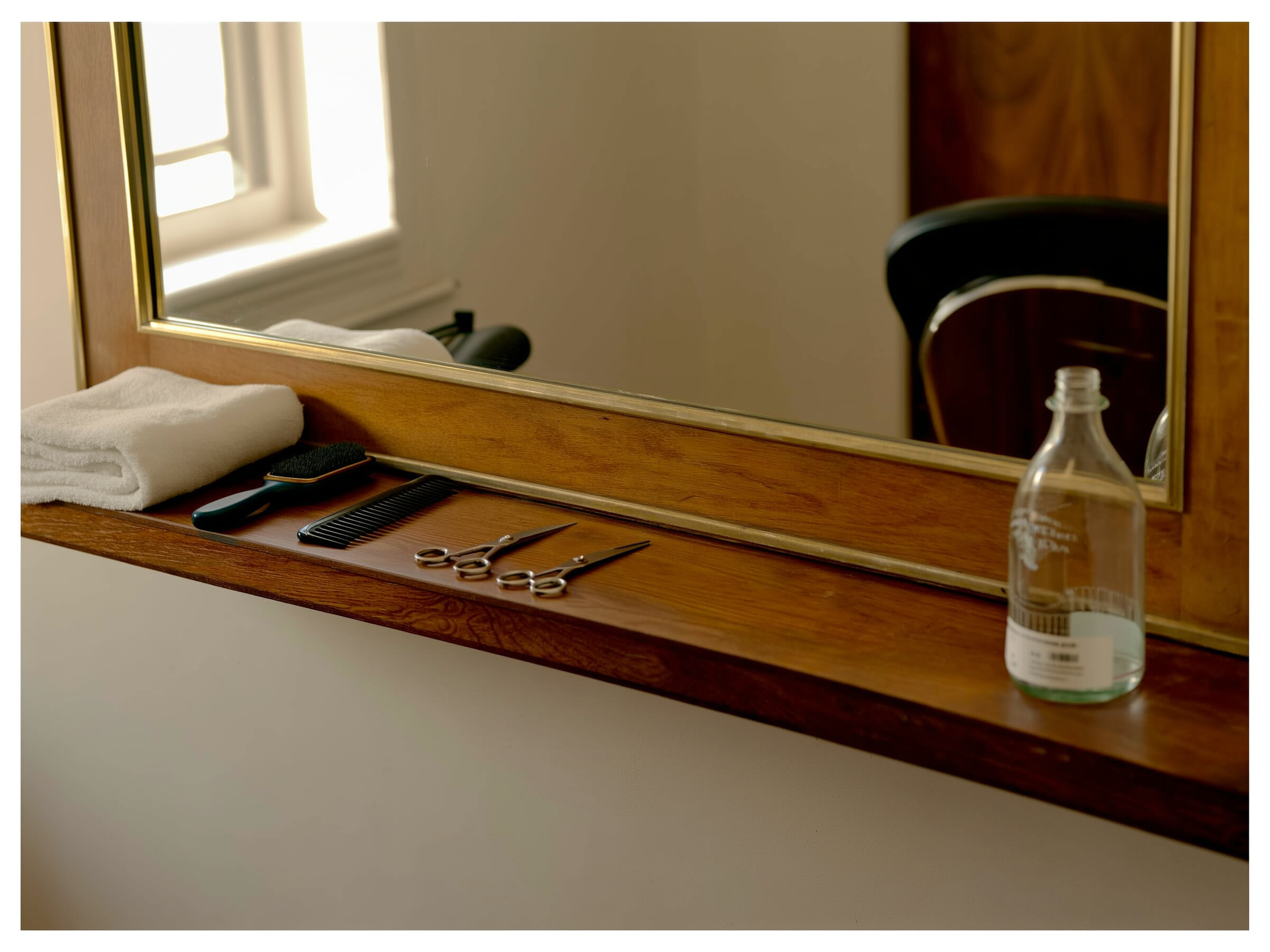 Houten kaptafel met een spiegel in een gouden lijst, opgevouwen handdoeken, een kam en een schaar